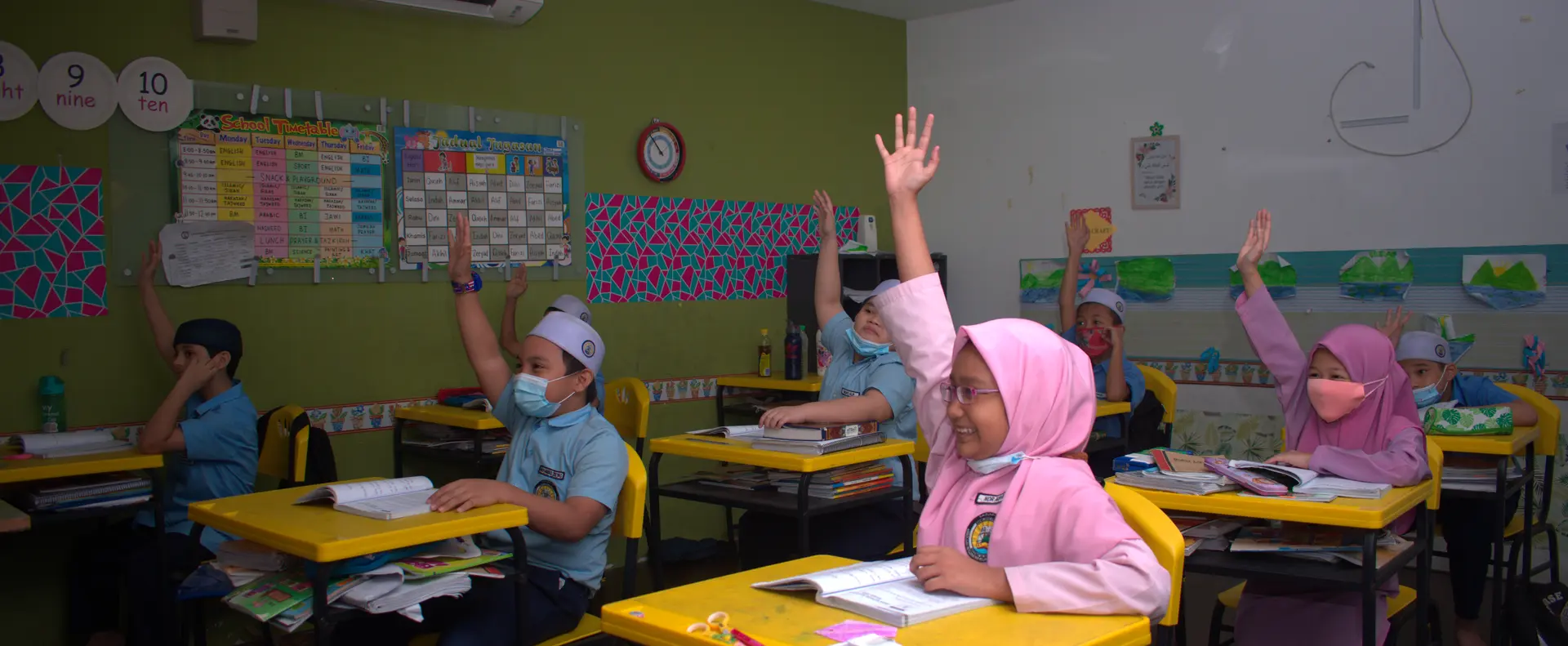 Murid sekolah rendah mengangkat tangan dalam kelas